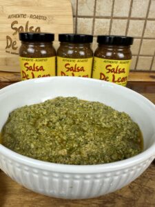 Spicy Basil Pesto in bowl in front of 3 jars of Salsa De Leon
